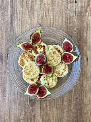 grilled figs plate with sliced figs and cheese rounds on a glass dish