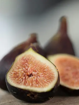 halved black mission fig with pink flesh beside whole figs