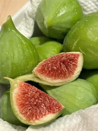 kadota green fig fruits with one sliced open showing pink-red flesh