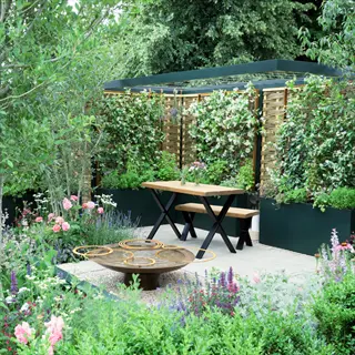 liatris container patio with wooden dining set, lush planters and flowering garden beds