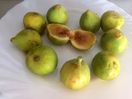 lsu gold fig fruits on a white plate, with one sliced open showing pink flesh