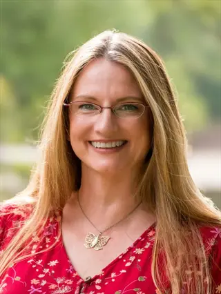 portrait of anne marie ivy smiling outdoors in a red floral top